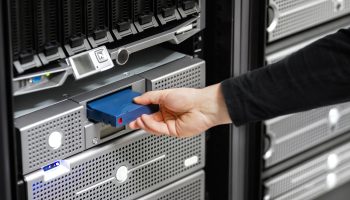 Cropped hand of mid adult male technician positioning hard drive in SAN at datacenter